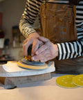 Person using 135 Piece 5 Inch Sanding Discs Set Eight Hole Round Hook And Loop Gold Pro Grade Grit for wood sanding