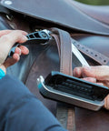 Hands adjusting Alupro Titanium Safety Stirrup with Side Opening Design and HiFlex Locking on a leather saddle