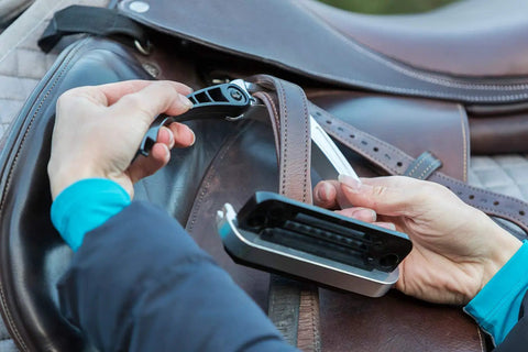 Hands adjusting Alupro Titanium Safety Stirrup with Side Opening Design and HiFlex Locking on a leather saddle