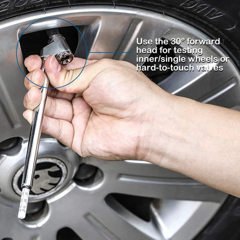 Pencil-style tire pressure gauge with stainless steel stem used to check a car tire valve on a silver alloy wheel