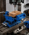 Heavy Duty Cross Slide Drill Press Vise Featuring Rock Solid Cast Iron Body And Smooth Operating Jaws For Precision Milling Tasks and Heavy Shop Grind Built Tough For Serious Jobs in workshop with wood piece.