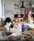 A woman holds Top Shelf Leather Cleaner And Conditioner Wipes With Cloth while sitting with a child and dog on a couch.