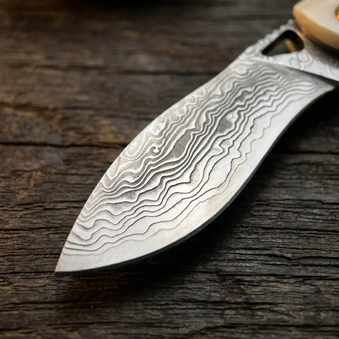 Close-up of Damascus steel blade texture on a Folding Pocket Knife With 2.99 Inch Damascus Steel Blade And Ivory Synthetic Handle Ultra Portable EDC Knife For Camping And Daily Home Use Built For Everyday Carry And Outdoor Adventures Great Gift For Men