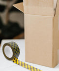 Plaid Pattern Shipping Tape 2 Rolls Adhesive Sealing Packing Tape With Black Yellow Grid Design For Small Business Mailing And Packaging Supplies Awesome For Crating Boxes Shipping Labeling And DIY Projects At Home Or Office next to open cardboard box