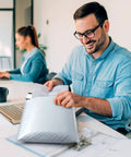 Man using Bubble Mailers 8.5x12 Inch White Pack Of 25, holding poly padded envelope at office desk, self-seal feature visible