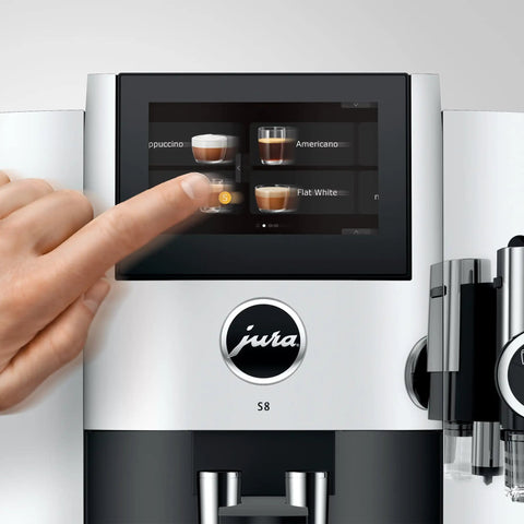 Premium Fully Automatic Chrome Espresso Coffee Machine Featuring A Hella Smooth Four Point Three Inch Smart Touchscreen Display For Twenty Seven Freshly Ground Drinks with user selecting a drink.