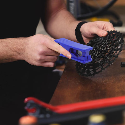 Blue TEHAUX bicycle hydraulic brake hose cutter tool in hand cutting a round black disc brake component.