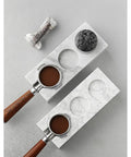 Top Shelf Marble Espresso Tamper Holder Stand Fits 51mm And 54mm Coffee Tools with espresso grounds on a marble base.