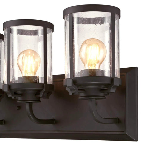 Close-up of three light indoor vanity light wall fixture in oil rubbed bronze with clear seeded glass for bathrooms or hallways.