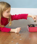 Girl placing coin in small pink cash box with key lock, double layer metal money box for home security, portable locking cash safe with tray.