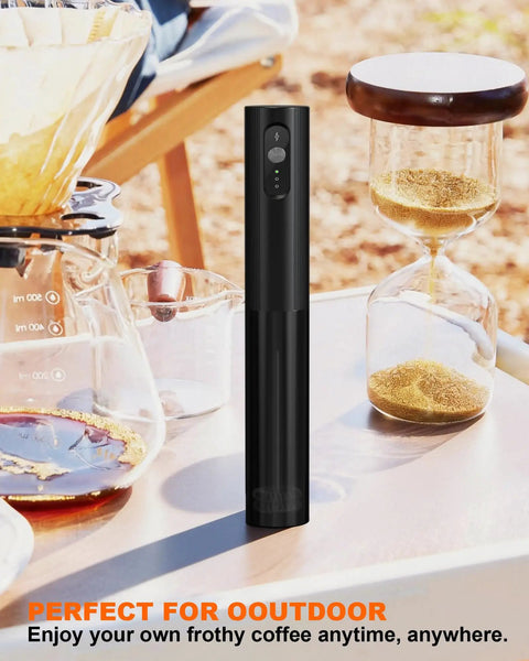 Soenglyun 3 Speed Rechargeable Milk Frother Handheld Press With Travel Cover Quiet Foam Maker For Latte Cappuccino Coffee Shop Quality Drink At Home Fast And Easy Use Cordless Battery Operated in black, placed on a table outdoors with coffee equipment.