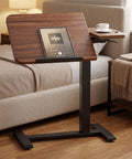 Tiltable Mobile Standing Desk With Wheels Pneumatic Height Adjustable Overbed Table in walnut next to bed, holding tablet and coffee