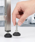 Hand holding Six Pack M10 Threaded Leveling Feet With Rubber Swivel Ball Joint Pads 50mm Base next to metal furniture leg