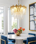 Next Level Two Layer Gold Crystal Glass Chandelier And Four Light Round Pendant Fixtures With Brushed Brass Finish above a dining table.