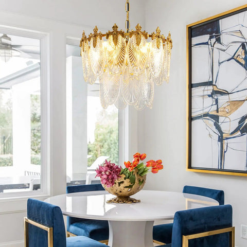 Next Level Two Layer Gold Crystal Glass Chandelier And Four Light Round Pendant Fixtures With Brushed Brass Finish above a dining table.