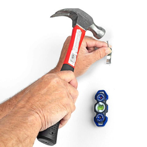 Man using hammer next to Magnetic Stud Finder Leveler With Built In Hang Hole Dual Level And Plumb Helper, compact blue tool