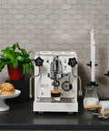 Next Level Home Bar Essentials Italian Handcrafted Espresso Machine With Heat Exchanger And E61 Manual Controls Badass Stainless Steel Chassis Three Liter Tank Fresh White Finish on kitchen countertop.
