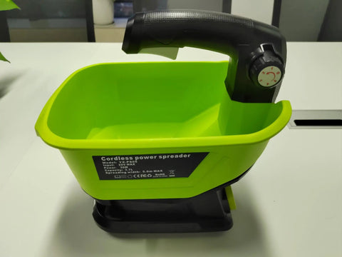 Cordless All Season Spreader for 18V Lithium Batteries on table, green container with black handle, year round yard care