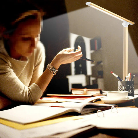 Must Have LED Desk Lamp With USB Charger, Dimmable Eye Caring Light on desk next to reading woman, providing focused light