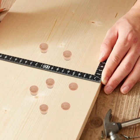 Wood board with 50 Pack DIY Wooden Hole Caps and Pocket Hole Plugs Hardwood Wood Plugs For Cabinets laid out next to a ruler.