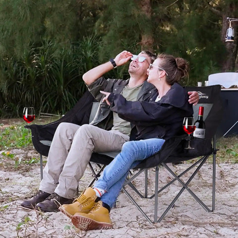 Two Person Camping Chair Loveseat Heavy Duty Double Folding Camp Couch For Adults With Wide Armrests And High Back Oversized Outdoor Sit For Two Supports Up To 650 Lbs Black in a forest setting, featuring a couple enjoying a picnic with wine glasses.