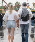 Couple wearing Disposable Rain Ponchos For Adults Waterproof Emergency Gear Clear One Size Fits All in amusement park