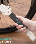 Hand holding Rotor Truing Fork 2 In 1 Bike Rotor Tool And Hydraulic Piston Press For Bicycle Disc Brakes, near bike wheel.