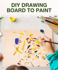 Wooden drawing board for painting; child hand with brush on light plywood panel with colorful abstract marks.