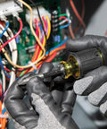 Gloved hands using Compact 3-Piece Tool Set with Mini Ratchet near electronics. Color coded and impact rated, for tight spaces.