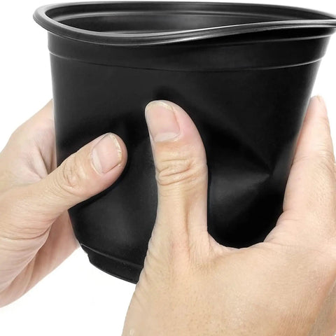 Hands squeezing a black pot from the 100 Piece Seedling Pots Set With 4 Inch Propagation Containers And Drainage Holes For Indoor Outdoor Gardening Starter Pots