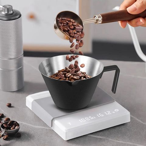 Two Pack Stainless Steel Espresso Cups With Handle, Double Spout Measuring Cup With Dual Scale, V Shaped Mouth, 3.4oz 100ml, Black Coffee Shot Cups being filled with coffee beans on a digital scale.