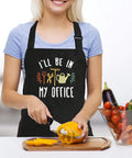 Woman slicing bell pepper wearing women waterproof adjustable bib apron with two pockets for kitchen and garden in black.