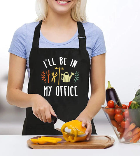 Woman slicing bell pepper wearing women waterproof adjustable bib apron with two pockets for kitchen and garden in black.