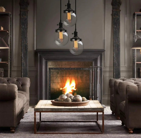 Three Light Industrial Cluster Pendant Ceiling Fixture With 5.9 Inch Clear Globe Shades In Black Finish above a living room.