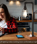 Woman using laptop beside Industrial Desk Lamp With Bulb Included, 3-Way Dimmable, Dual USB Ports And AC Outlet in kitchen.