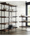 Built Different Wrought Iron Bookshelf With Thick Wood Shelves Hella Sturdy Floor Stand displaying wine glasses and dishes.
