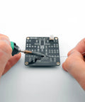 Hands soldering a PCB from an Electronic Dice Soldering Kit For Beginners And Students DIY LED Dice Circuit With 555 Timer And CD4017 Counter