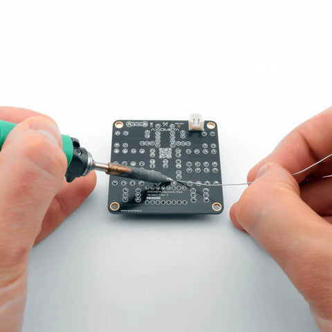 Hands soldering a PCB from an Electronic Dice Soldering Kit For Beginners And Students DIY LED Dice Circuit With 555 Timer And CD4017 Counter