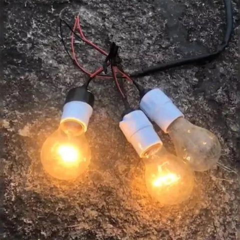 Three clear light bulbs connected by wires, glowing on a rough surface.
