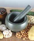 Granite Mortar And Pestle Set 6.3 Inch Black Grinding Stone For Spices Herbs Pesto Garlic Nuts Anti Slip Base Easy To Clean Durable Kitchen Must Have For Crushing Pills And Grinding Fresh Flavors surrounded by ingredients