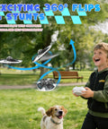 Child flying UFO Hand Controlled Drone For Kids, Safe RC Toy With 7 LED Lighting Modes, 360 Degree Flips, in a park setting with dog.