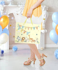Woman holding 13 inch large baby gift bag for baby shower with tissue paper and greeting card yellow dinosaur design
