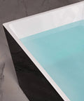 Close-up of Contemporary 67 Inch Freestanding Acrylic Soaking Bathtub With Matte Black Drain and Overflow with water.