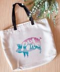Canvas tote with a colorful pig design on wooden surface with floral decor