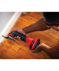 Person using Cordless Oscillating Tool Kit With Blades, Sandpaper, Battery And Charger Included for precise cutting on wooden floor