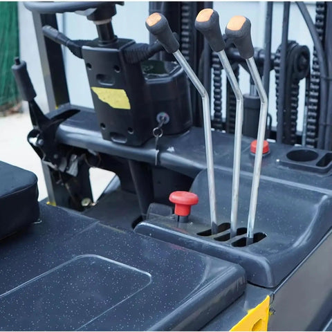 Compact Electric Forklift Two Point Five Ton Load Capacity Side Shift Steering controls and hydraulic levers for operation.
