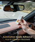 Person holding Heavy Duty Adhesive Mounting Strips For Ezpass Sunpass And Dash Cams in car interior with dashboard view.
