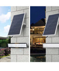 JUDYSSY Solar Powered Street Flood Lights Outdoor Led Waterproof Lamp with Remote Control mounted on wall, showing solar panel and light.