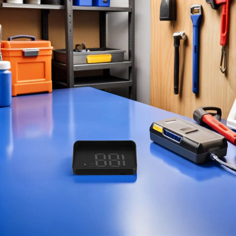 Vehicle Speedometer Display With Green LCD For Cars, Universal HUD Head Up Display on a blue workbench in a garage.