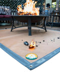 Under Grill Fire Pit Mat For Outdoor Deck And Grass Protection with fireproof BBQ pad under a lit fire pit on a patio.